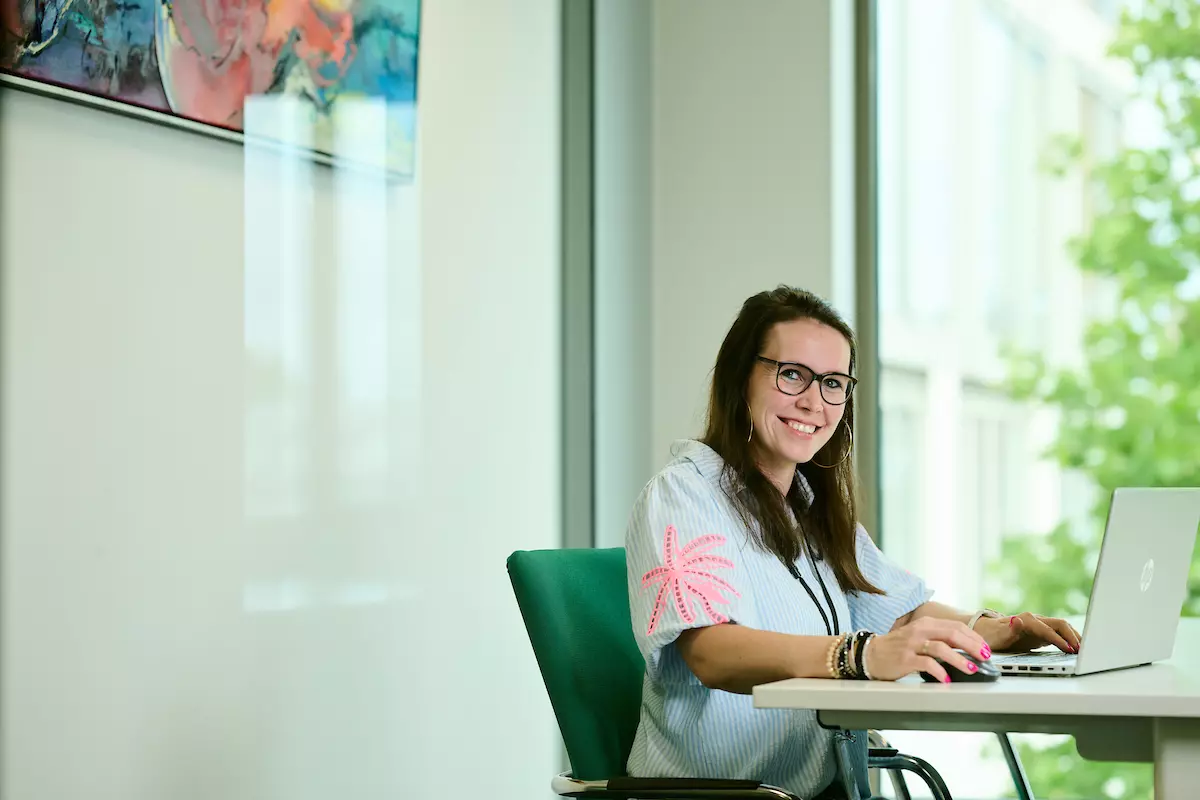 Collega projectenbureau Joyce zit lachend achter haar bureau